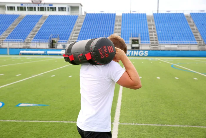 Athlete on a football field using the Hampton Compound Sandbag
