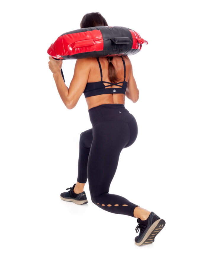 female athlete lunging with a black and red hero strength rescue bag