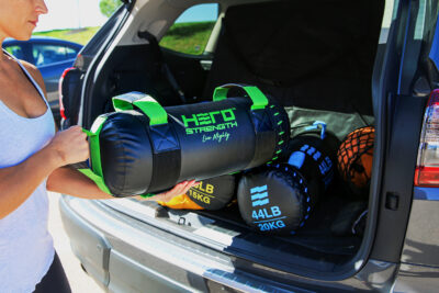 female loading hero strength bags into the trunk of an suv