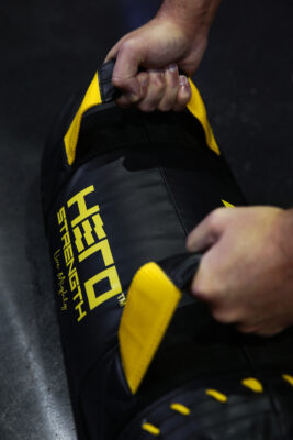 athlete gripping a black and yellow weighted bag