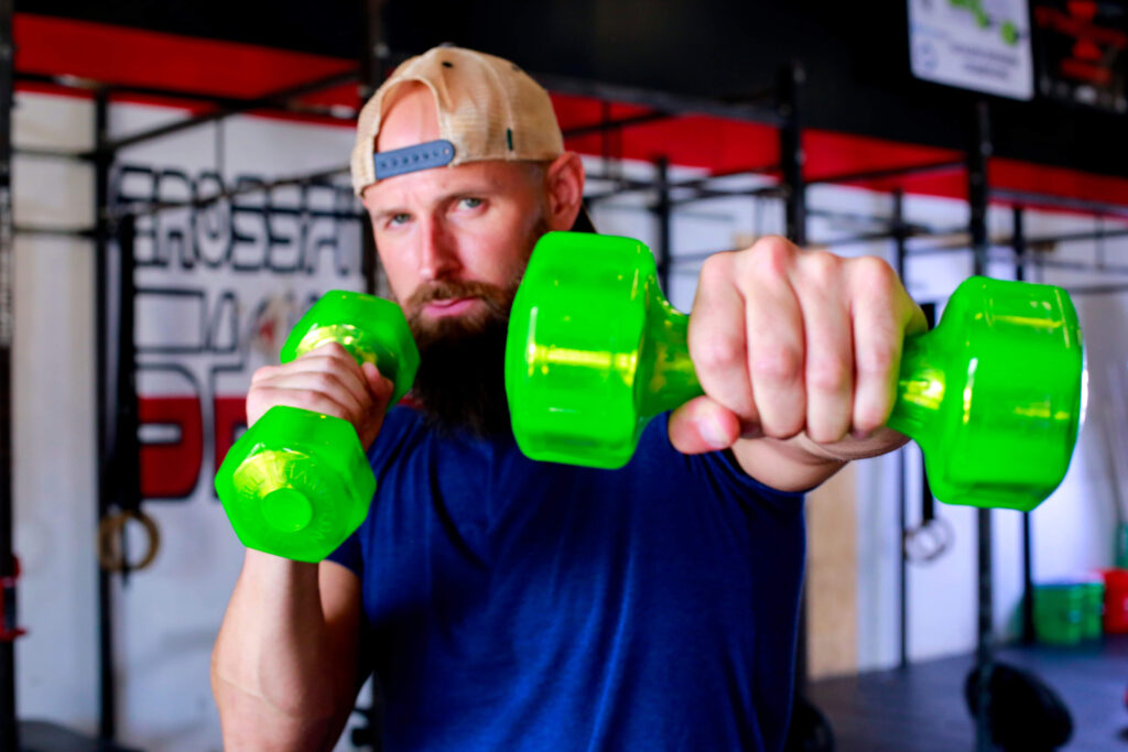 male athlete doing a shoulder workout with green jelly bells