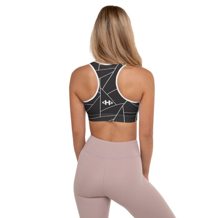 blonde woman, black and white racerback bra with geometric designs, facing back and muted mauve leggings