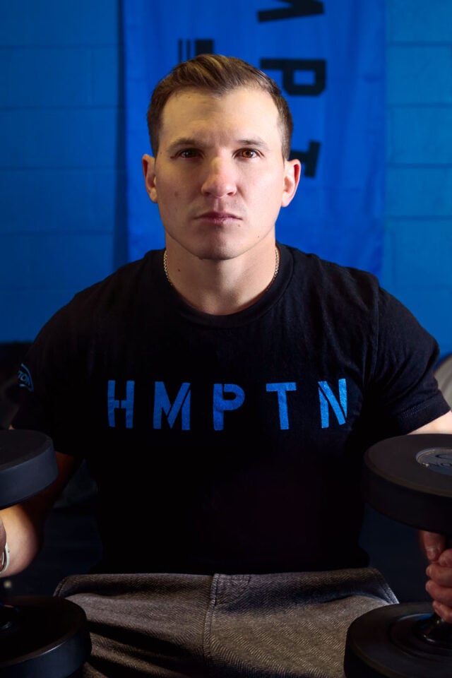 Male in black hampton fitness HMPTN shirt with blue stencil style lettering