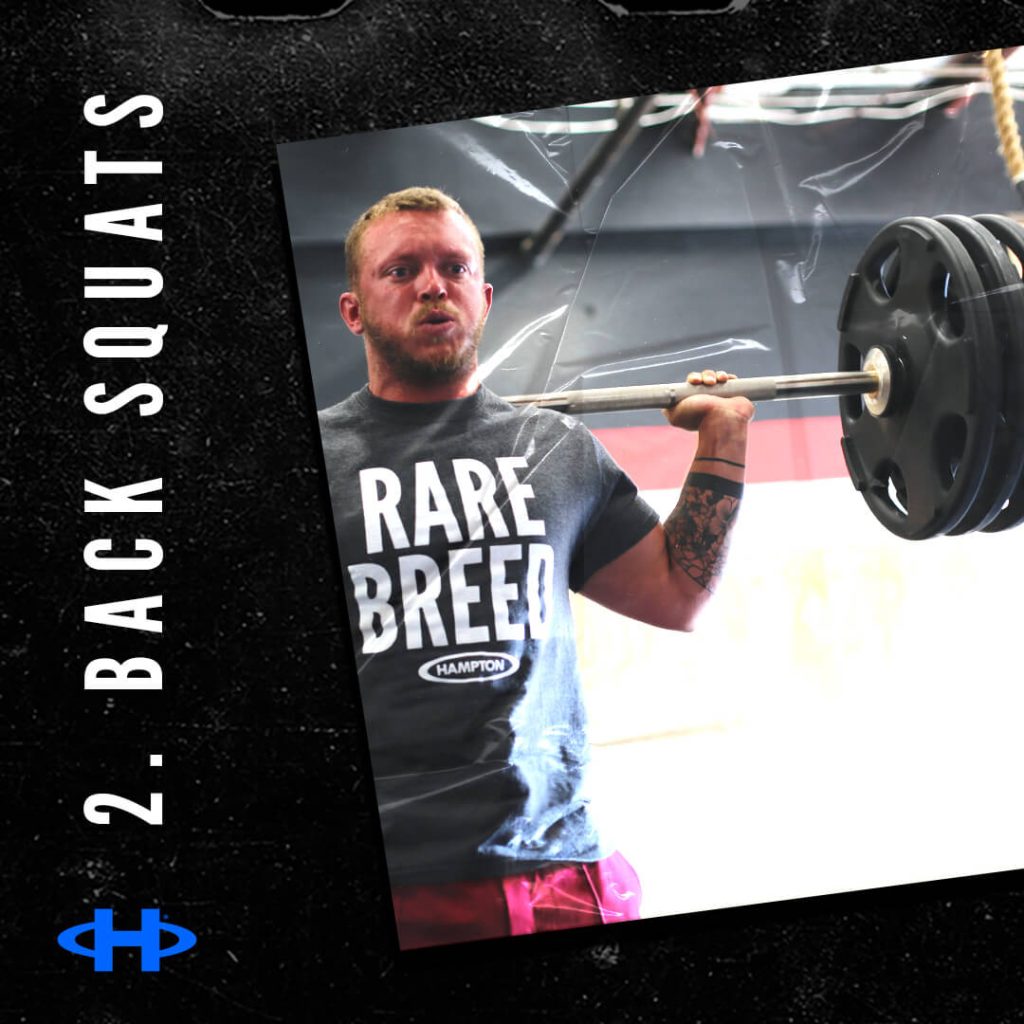Man wearing a "Rare Breed" shirt lifting a barbell with weights on it.
